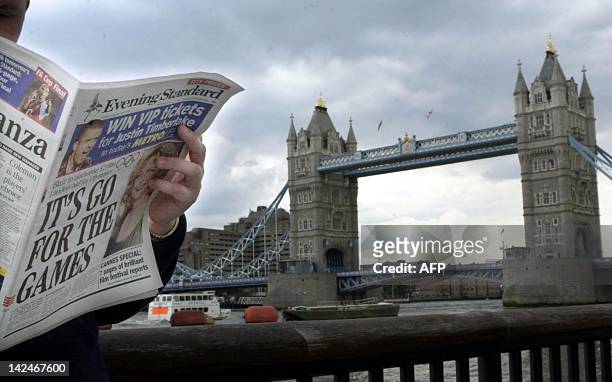 Londoner reads the Evening Standard near Tower Bridge 15 May 2003 in London, after British premier Tony Blair gave the go-ahead today to a 3,85...