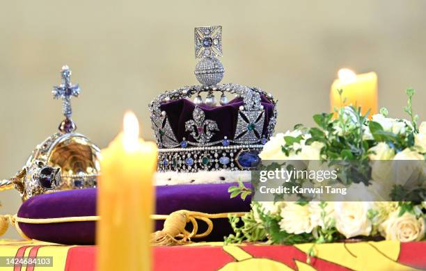 The coffin carrying Queen Elizabeth II is draped in the Royal Standard and adorned with the Imperial State Crown and the Sovereign's orb and sceptre...