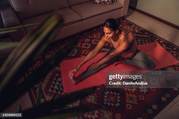 werdende mutter beim yoga auf der übungsmatte zu hause - pregnant yoga stock-fotos und bilder