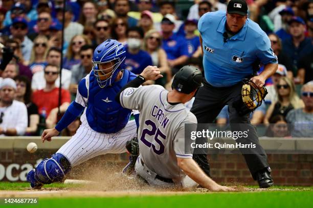 Cron of the Colorado Rockies beats the ball at home plate to score in the seventh inning against P.J. Higgins of the Chicago Cubs at Wrigley Field on...