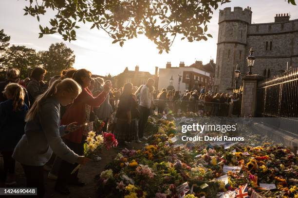 People gather at the gates of Windsor Castle to lay flowers in tribute to Queen Elizabeth II on September 17, 2022 in Windsor, England. Queen...