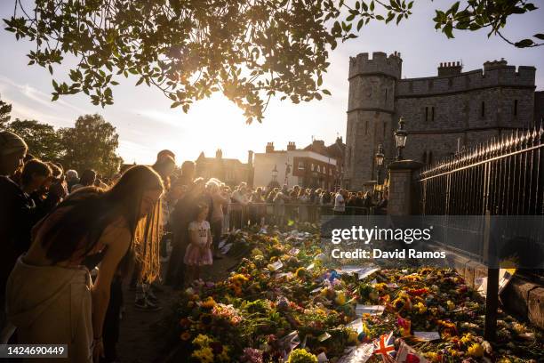 People gather at the gates of Windsor Castle to lay flowers in tribute to Queen Elizabeth II on September 17, 2022 in Windsor, England. Queen...