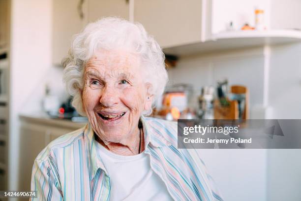 portrait of a beautiful, sharp, intelligent 101-year-old elderly senior caucasian woman looking away from camera and grinning indoors - 100 stockfoto's en -beelden