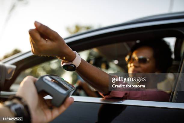 selective focus shot of woman using smart watch to pay for drive through order - drive through stock pictures, royalty-free photos & images