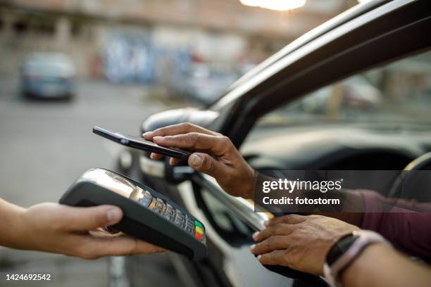 woman paying with smart phone at the drive through - drive through stock pictures, royalty-free photos & images