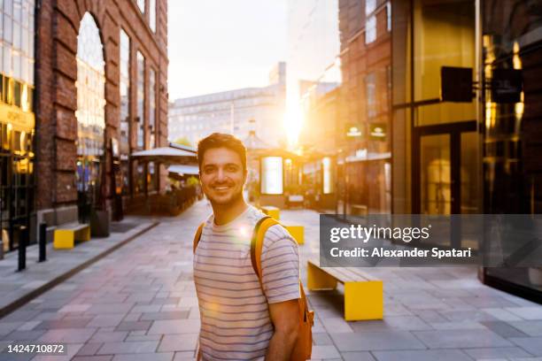 young happy smiling man on the street at sunset, oslo, norway - goldene stunde stock-fotos und bilder