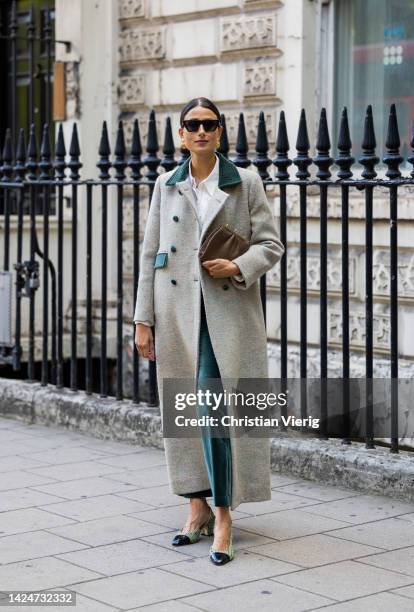 Julia Haghjoo wears double breasted coat, green pants, clutch, heels Chanel outside Paul & Joe during London Fashion Week September 2022 on September...