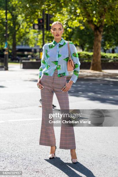 Alina Baikova wears checkered pants, blue green blouse with print, Chanel bag outside Paul & Joe during London Fashion Week September 2022 on...