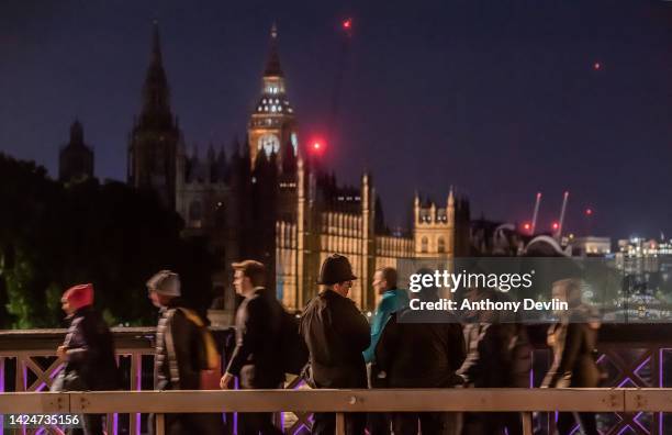 Police officers look-on as members of the public queue along Lambeth Bridge as they wait to pay their respects to Queen Elizabeth II as she lies in...