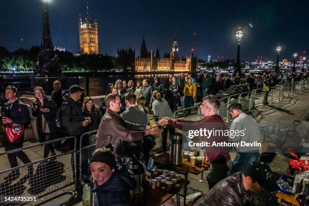 Group of friends hand out hot drinks to members of the public as they queue along Albert Embankment opposite the Houses of Parliament as they wait to...