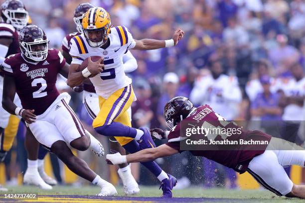 Jayden Daniels of the LSU Tigers runs with the ball as Jett Johnson of the Mississippi State Bulldogs defends during the first half of a game at...