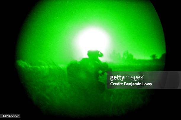 Soldier takes cover as an American helicopter uses a powerful light to search for Iraqi insurgents as Soldiers with the 509th Infantry Division and...
