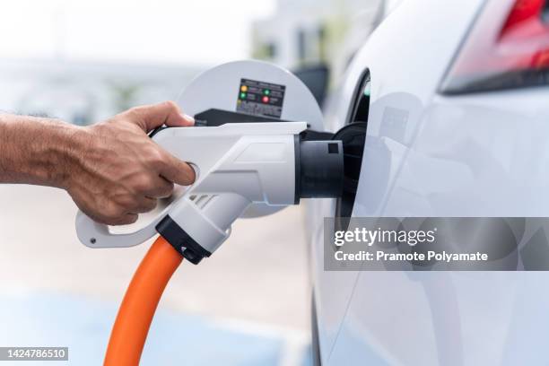 hand of human electric car at recharging station. eco-friendly sustainable energy concept. ev vehicle. - umweltfahrzeug stock-fotos und bilder