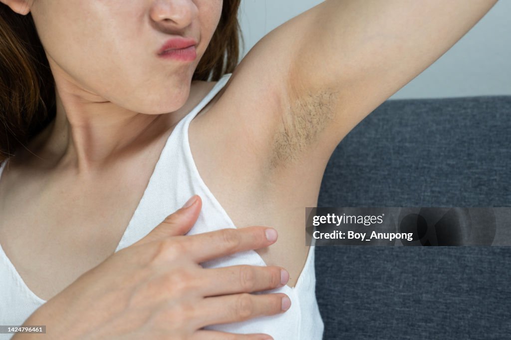 Cropped shot of Asian woman showing her unshaved armpit.