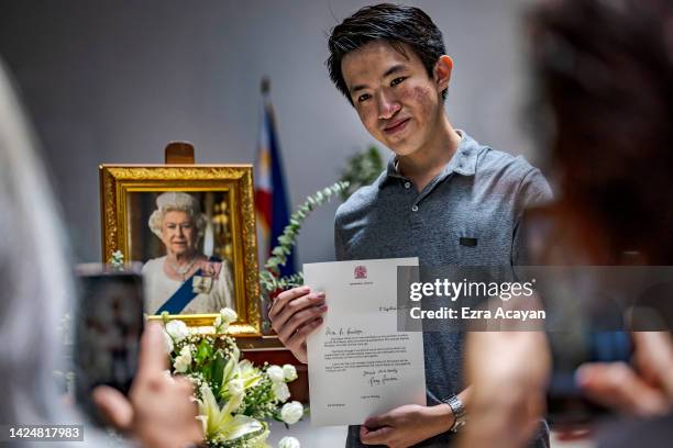 Man shows a letter he received from Balmoral Castle next to a portrait of the late Queen Elizabeth II following a memorial service at the Holy...