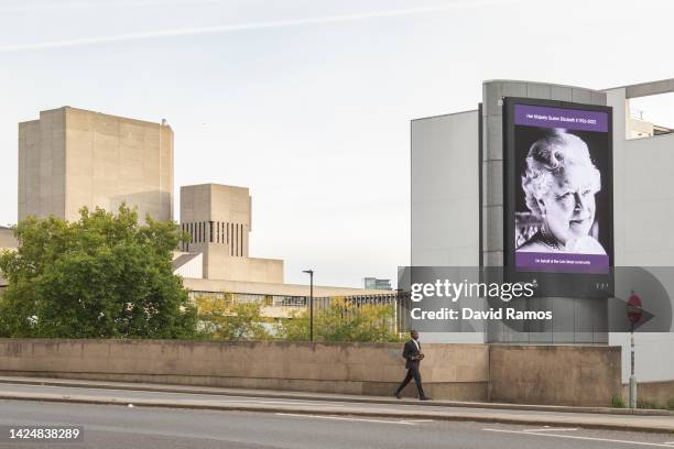 Man walks past a picture of Britain's late Queen Elizabeth II on September 18, 2022 in London, United Kingdom. Queen Elizabeth II is lying in state...