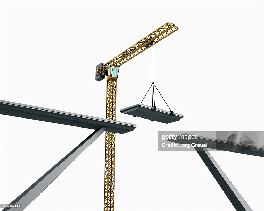A bridge being assembled by a crane