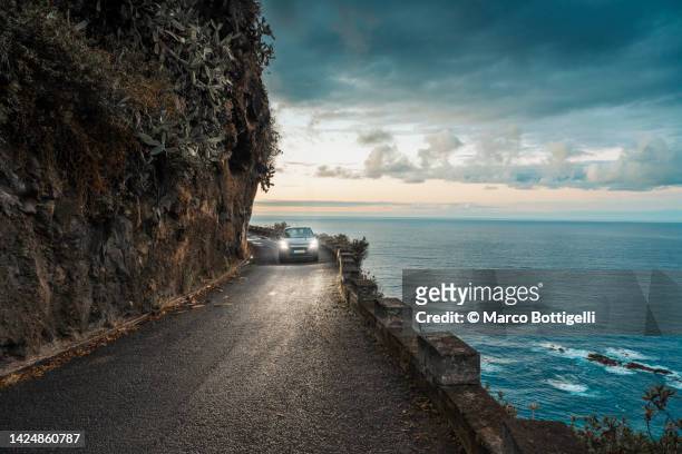 car driving on coastal road at dusk - car sunset stock pictures, royalty-free photos & images