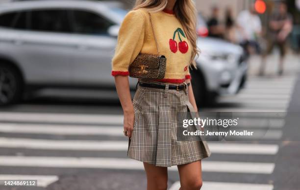 Emili Sindlev seen wearing statement wool sweater with cherries and plaid skirt, outside coach during new york fashion week on September 12, 2022 in...
