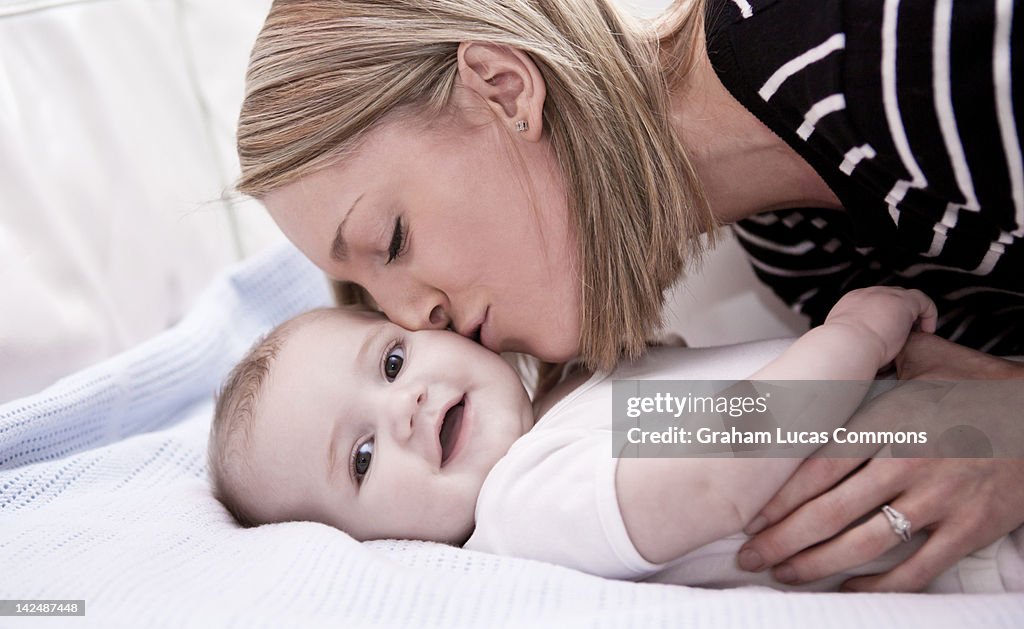 Mother kisses baby son in bed