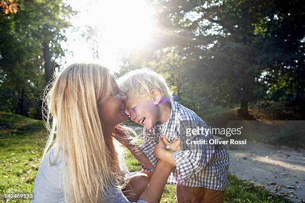 mother and her child cuddling in a park - blonde hair boy stock pictures, royalty-free photos & images