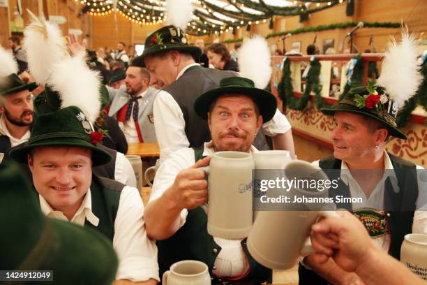 Folk group from Upper Bavaria sits together for drinking out of 1 liter beer mugs at the Tradition tent on day two of the 2022 Oktoberfest beer fest...