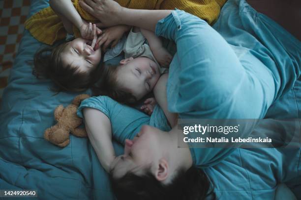 tired mother is resting with her sibling children. - baby close up bed stockfoto's en -beelden