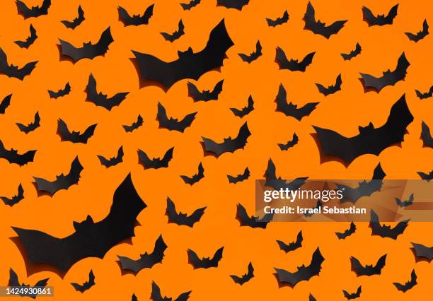 image of a large group of handmade black bats made of paper on a plain orange background. halloween concept. - fladdermus bildbanksfoton och bilder