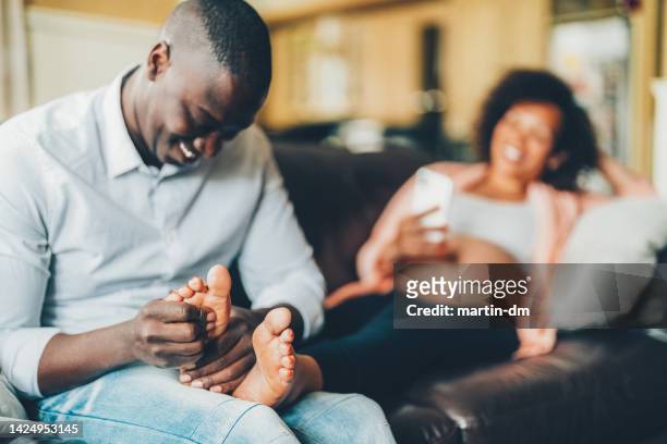 husband massaging his wife's feet - pampers stockfoto's en -beelden