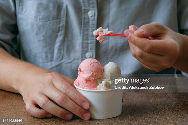 a young man, a guy eats ice cream in a cafe, cafeteria, in a chain of fast food restaurants. vegan ice cream in the hands of a high school student. vanilla and berry sherbet, dessert. the concept of rest and relaxation, vacations. dependence on sweets. - georgian man stock pictures, royalty-free photos & images
