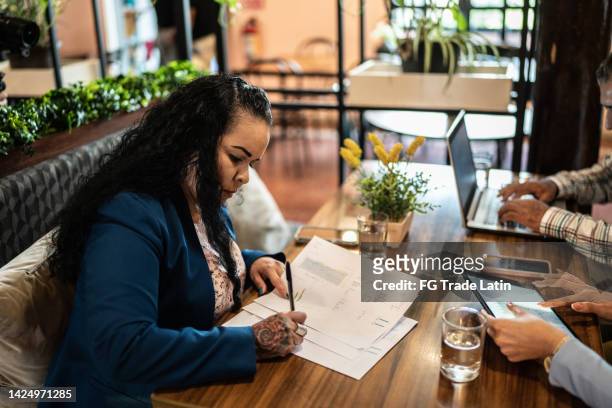 businesswoman sign a document during a meeting in a restaurant - pact for mexico stock pictures, royalty-free photos & images