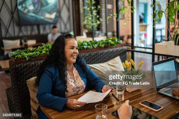 mature businesswoman having a meeting with coworkers at a restaurant - latin beauty stockfoto's en -beelden