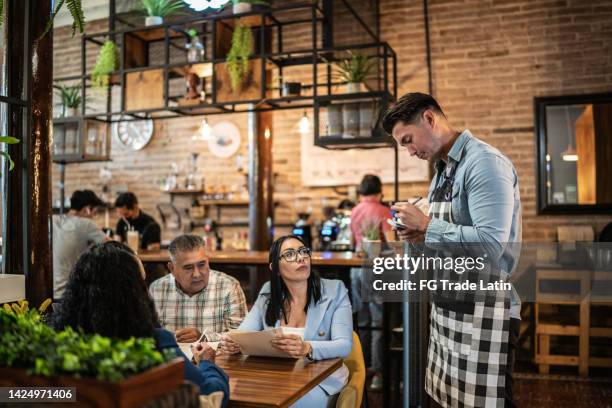 waiter taking order from customers at a restaurant - cafe staff stock pictures, royalty-free photos & images