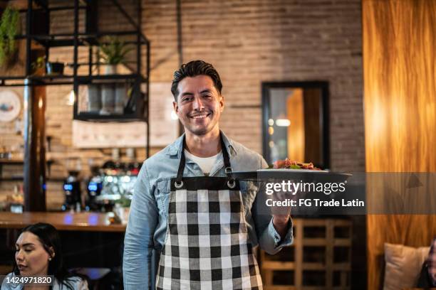 retrato de camarero llevando un plato terminado en un restaurante - camarero fotografías e imágenes de stock