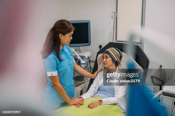 an asian health worker holding hands of cancer patient in hospital during receiving treatment - radiotherapy stock pictures, royalty-free photos & images
