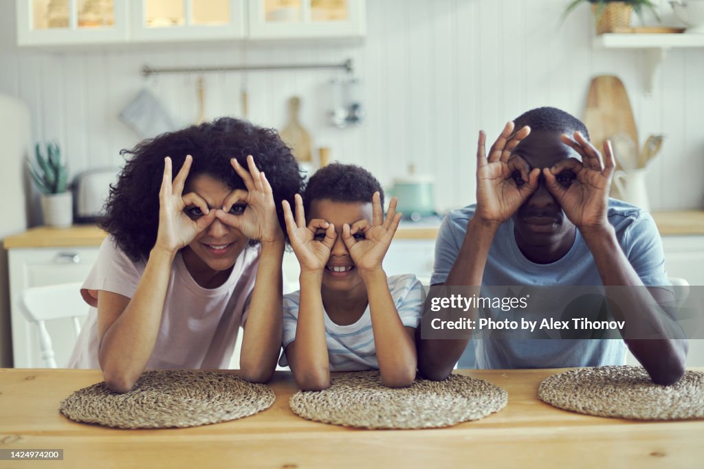 Parents and son making with fingers eyewear shape smile look at camera advertise eyewear lenses