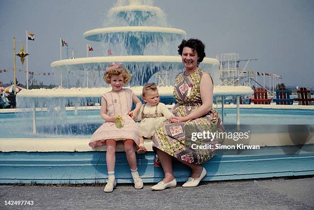 mother and two daughters sitting by fountain - butlins fotografías e imágenes de stock