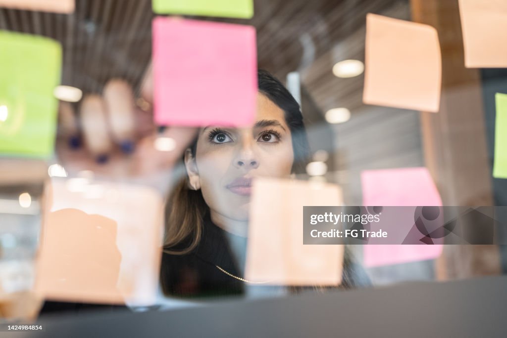 Junge Frau schreibt in Post it im Büro