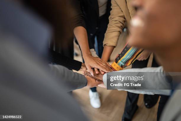 coworkers with stacked hands at the office - hands together stock pictures, royalty-free photos & images