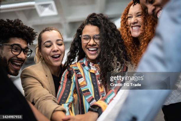 compañeros de trabajo con las manos apiladas en la oficina - employment issues fotografías e imágenes de stock