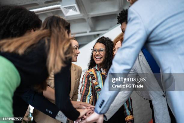 coworkers with stacked hands at the office - hand stack stock pictures, royalty-free photos & images
