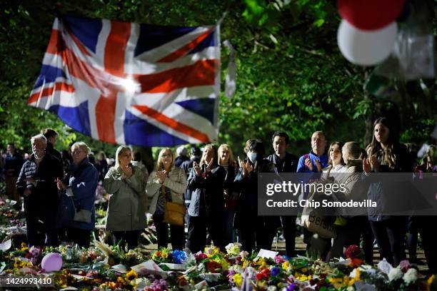 People applaud after observing one minute of silence and reflection on the life of Queen Elizabeth II in the floral tribute area in Green Park near...