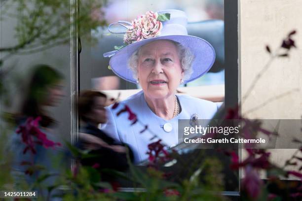 People walk by an image of Queen Elizabeth II displayed in a shop window on Oxford Street on September 18, 2022 in London, England. Queen Elizabeth...