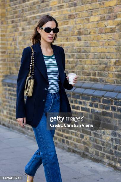 Alexa Chung wears navy blazer, denim jeans, striped shirt, Chanel bag, yellow heels outside Nensi Dojaka during London Fashion Week September 2022 on...