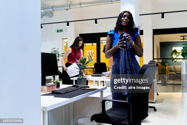 young well-dressed black female executive in the office accompanied by her colleague, a young caucasian woman who is organizing some documents. - vice president office stock pictures, royalty-free photos & images