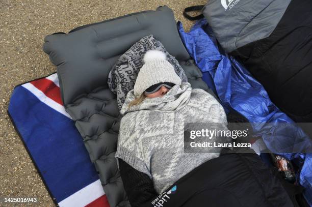 Woman sleeps in her sleeping bag on The Mall to occupy a seat near the barriers and ensure a view for the last farewell to the Queen at the funeral...