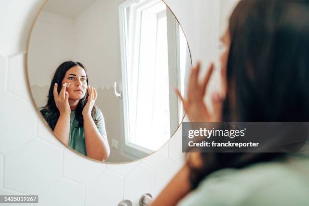 femme se maquillant dans la salle de bain - image teintée photos et images de collection