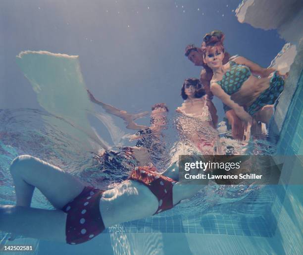 Underwater view looking up at a group of swimwear models in, and around a swimming pool, Palm Springs, California, 1964. The photo was taken for an...