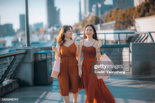 two happy asian women holding shopping packages on the shanghai bund,conceptual photo - woman shopping china photos et images de collection