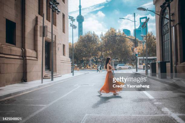 one beautiful young asian woman carrying camera walking through shanghai bund street,capturing an image - shanghai tourist stock pictures, royalty-free photos & images